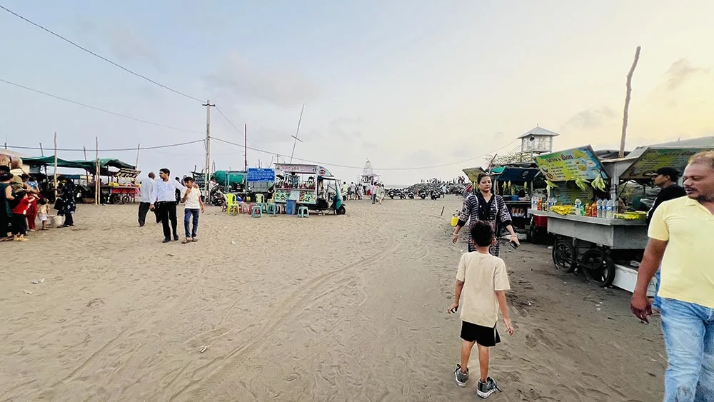 Dumas Beach Surat entry view with food stalls and visitors on sandy beach