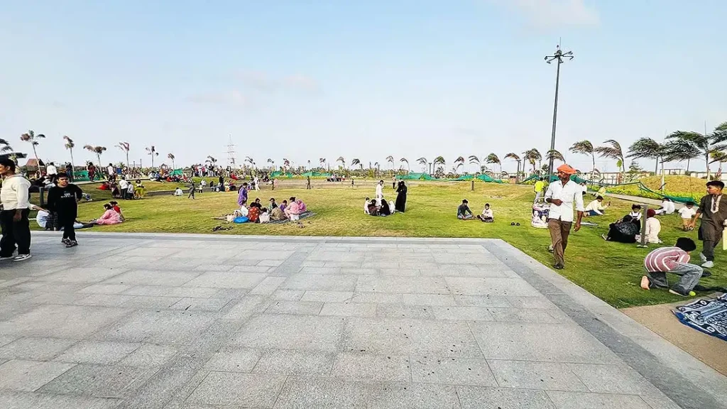 Families relaxing on green grass garden at Dumas Sea Face Surat