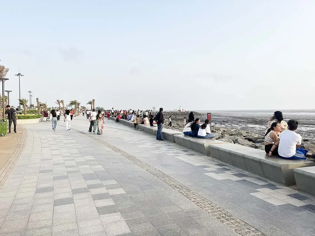 People sitting and relaxing along Dumas Sea Face seafront in Surat