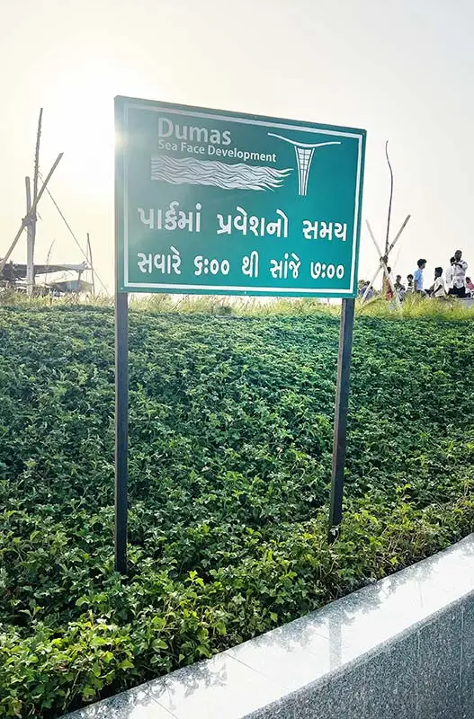 Dumas Sea Face timing board showing park entry hours in Gujarati