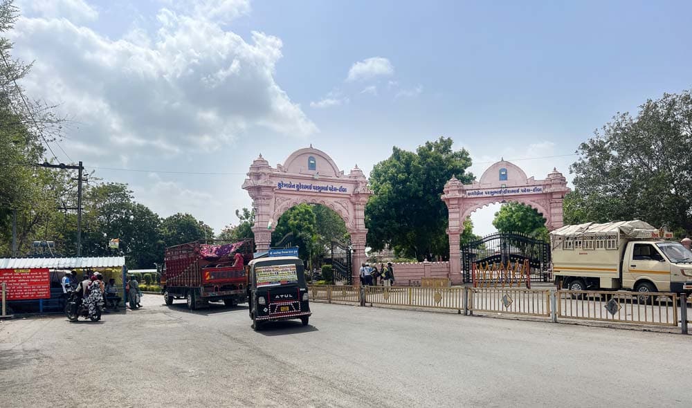 Pink arched entrance gate of Galteshwar Mahadev Temple with vehicles parked outside