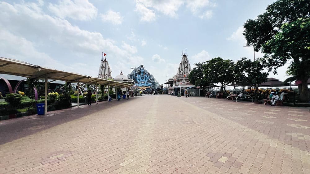 Wide angle view of the spacious courtyard at Galteshwar Mahadev Temple with statue and shikharas