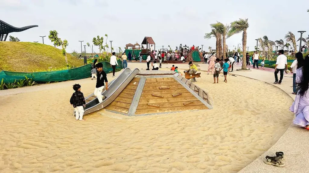 Children playing on wooden slide at Dumas Sea Face children's play ground