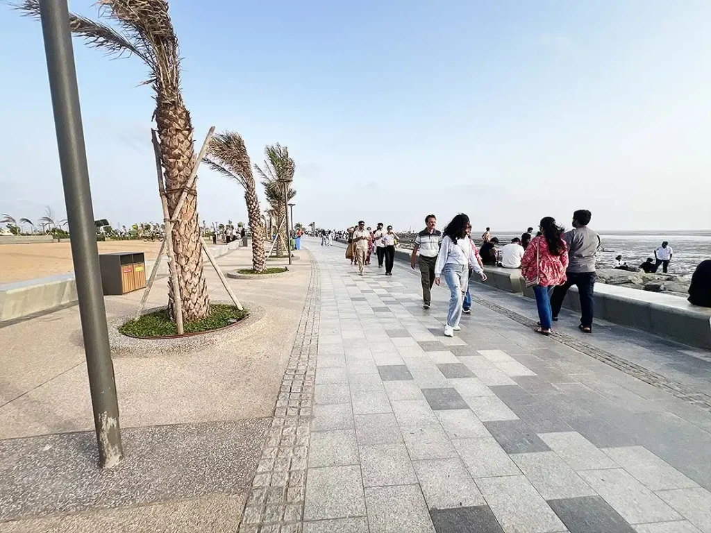 People walking on the paved footpath at Surat Dumas Sea Face